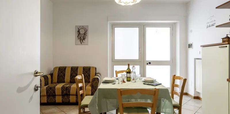 A dining area with a set table and a patterned sofa beside the window.