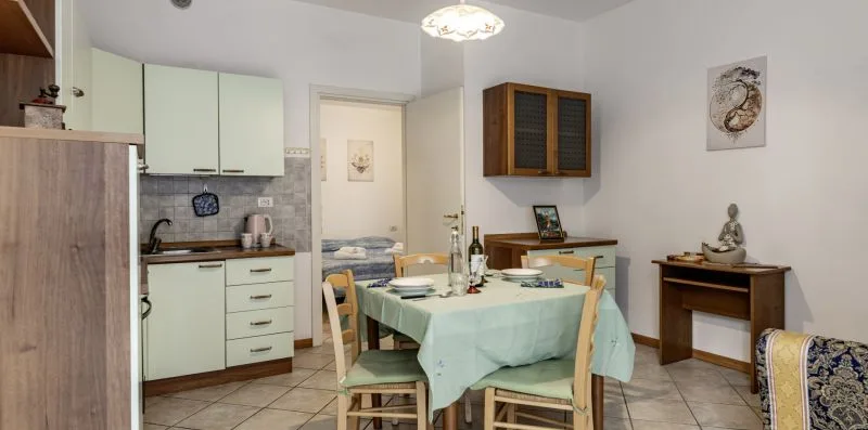 Comedor con una mesa puesta junto a una cocina compacta.