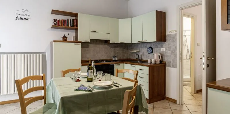 Una cocina y comedor con gabinetes claros y una mesa preparada para comer.