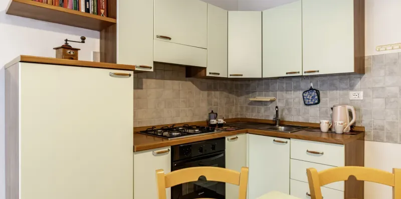 A kitchen with pale cabinets, a tiled backsplash, and a dining table.