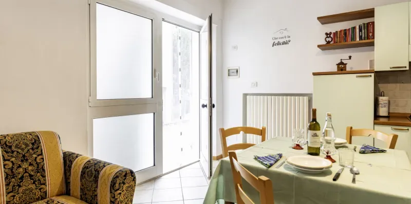A dining area with a set table and chairs beside an open glass door.