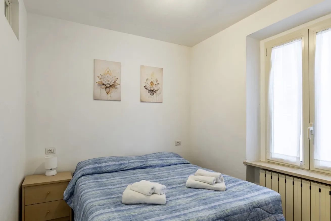 A bedroom with a blue striped bed and a bright window.
