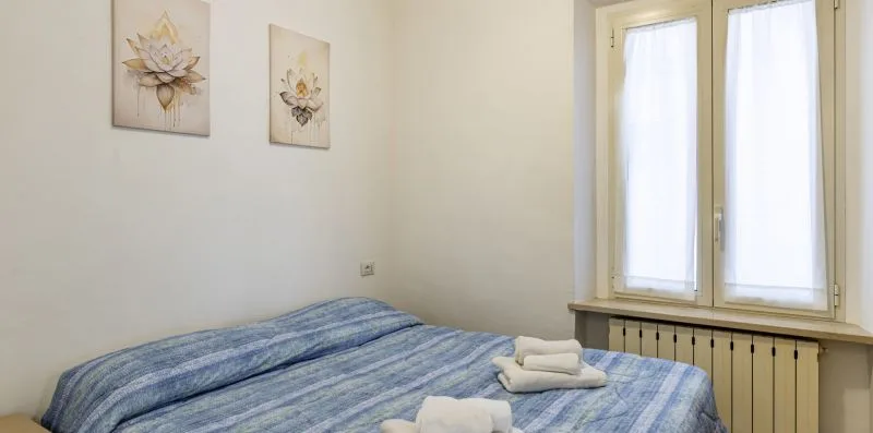 A bedroom with blue-striped bedding and a window.