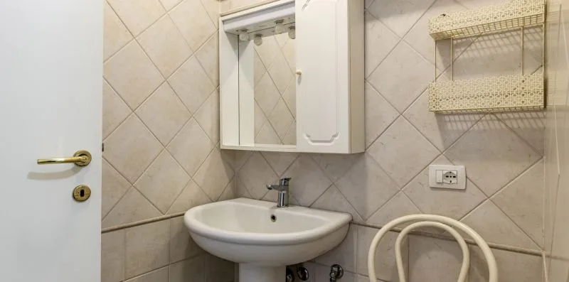 A tiled bathroom with a wall-mounted sink and mirror cabinet.