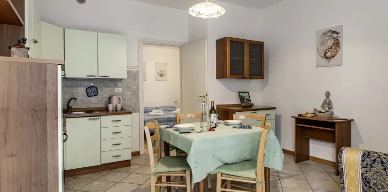 A dining area with a set table sits beside a compact kitchen.