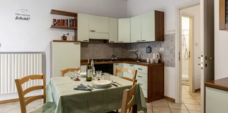 A kitchen and dining area with cabinets, a table, and wooden chairs.