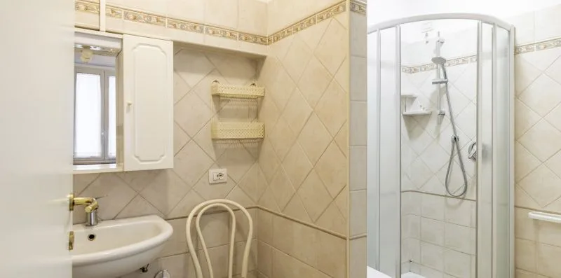 A tiled bathroom with a sink and glass-enclosed shower.
