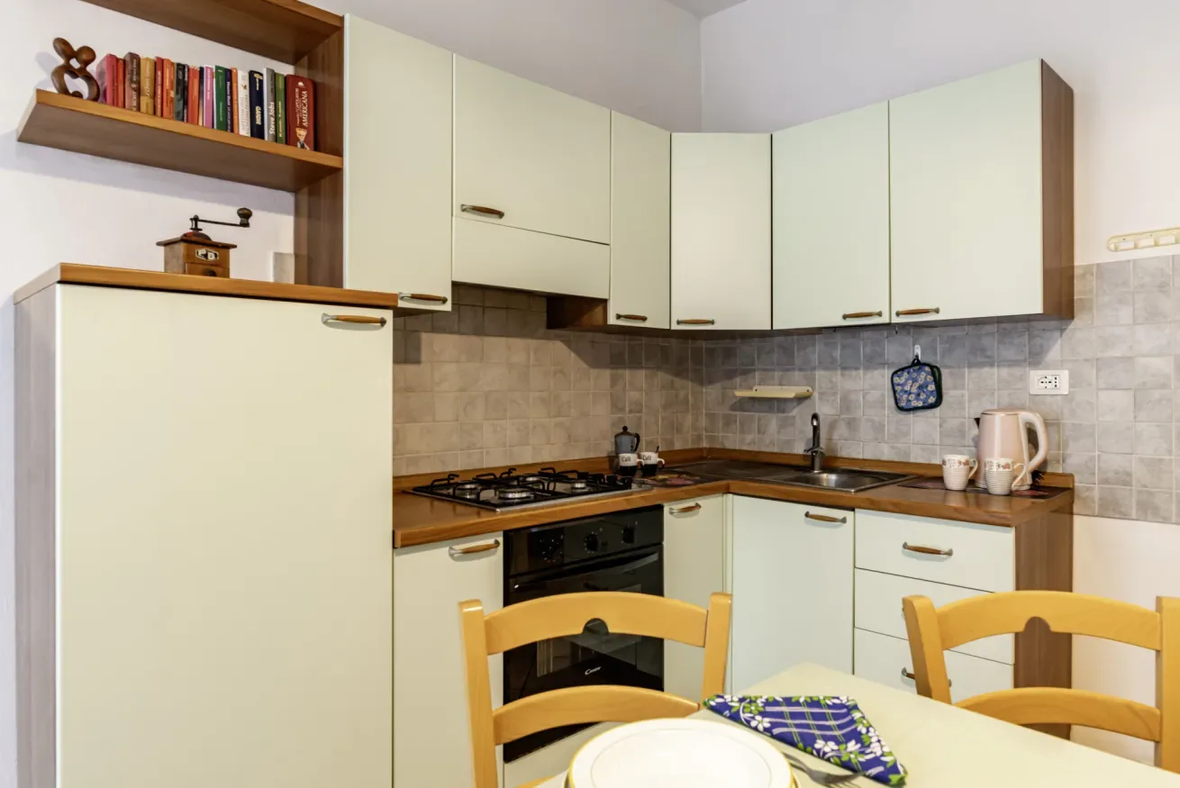A compact kitchen with pale cabinets, a cooktop, and a dining table.