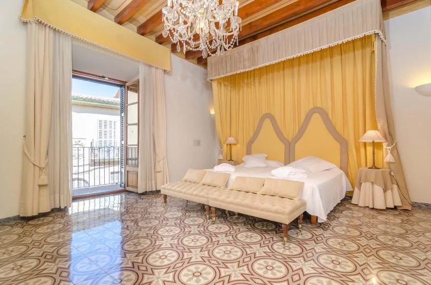 A bedroom with two beds, a cushioned bench, and floor-to-ceiling curtains.