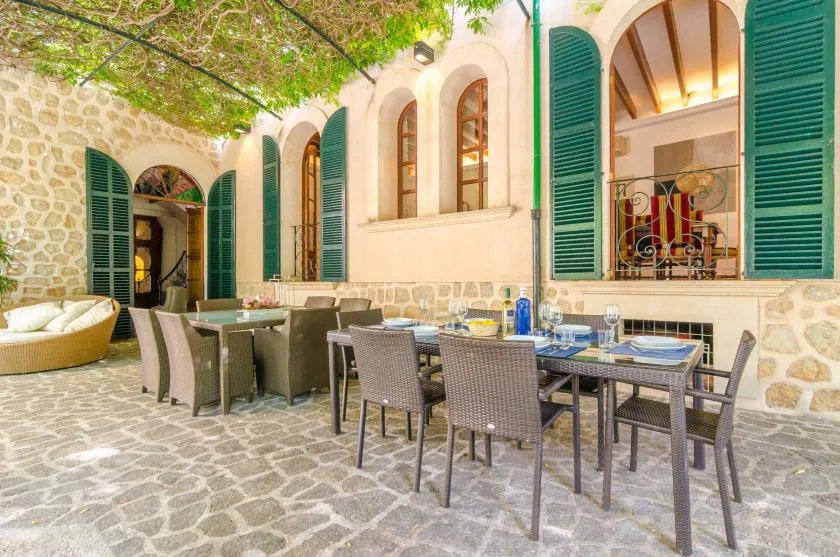 An outdoor dining area with tables and seating beside a stone building.