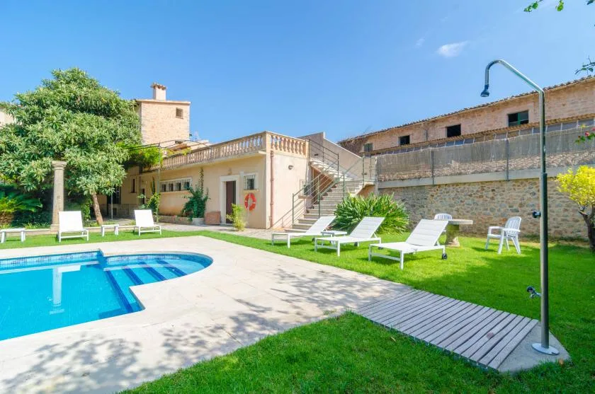 An outdoor pool area with lounge seating and a stone building.
