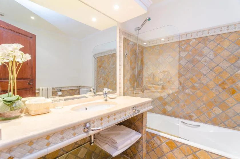 A bathroom with a wide sink counter and a bathtub beside tiled walls.