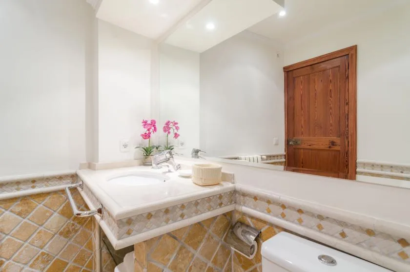 A tiled bathroom vanity with a sink, flowers, and a wooden door.