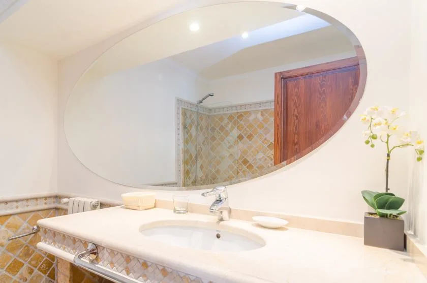 A bathroom vanity with a large oval mirror and a sink.