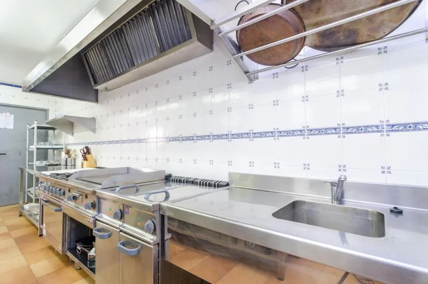 A commercial kitchen with stainless steel counters and cooking equipment.