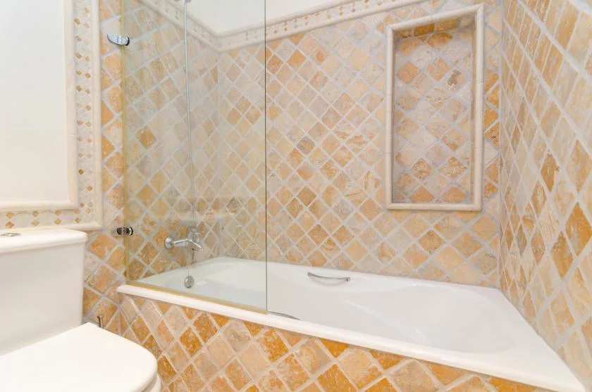 A tiled bathroom with a bathtub and shower fixtures.
