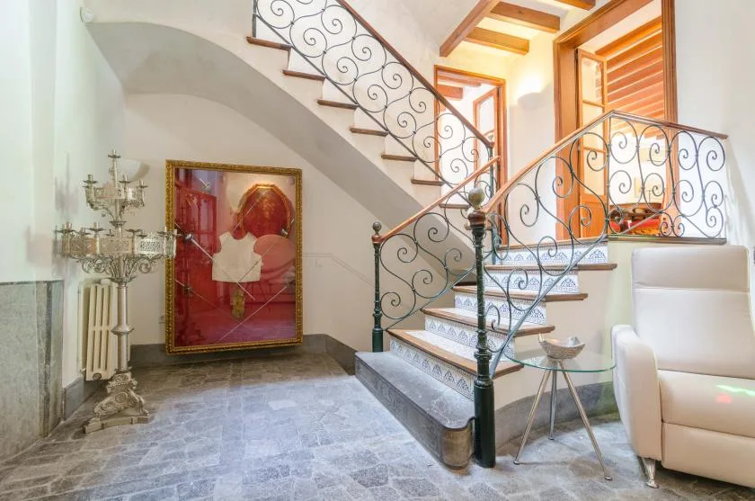 An interior stairway with decorative railings and a framed artwork beneath the stairs.