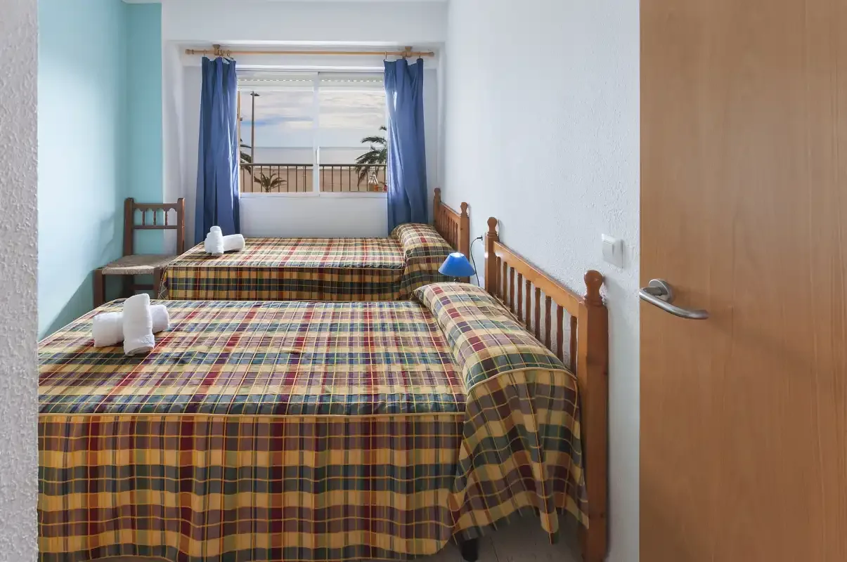 A bedroom with two beds covered in colorful plaid bedding.