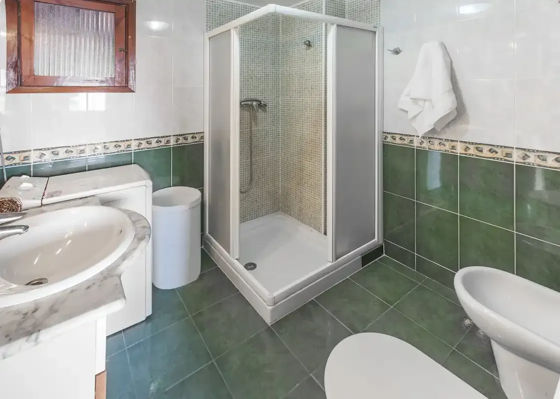A tiled bathroom with a shower, sink, and toilet.