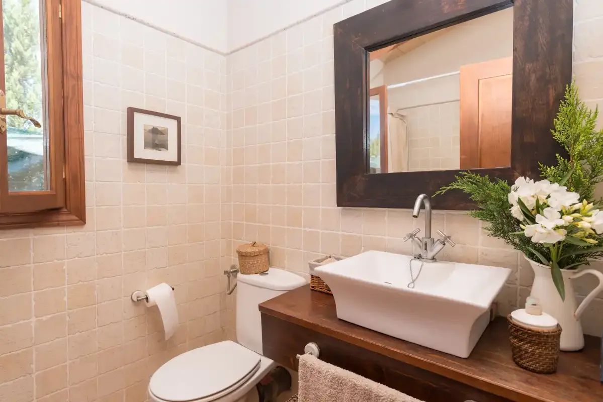Un baño con lavabo, espejo e inodoro.
