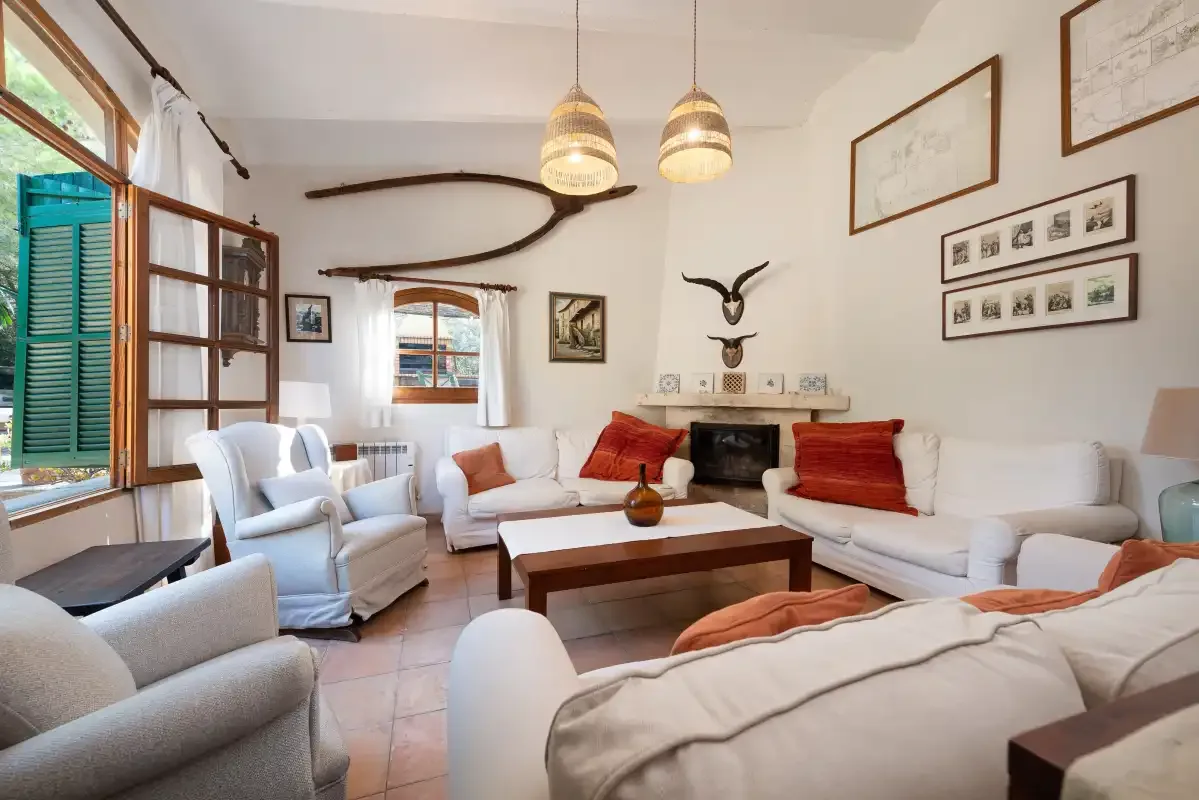 Una sala de estar luminosa con asientos claros alrededor de una mesa de centro y una chimenea.