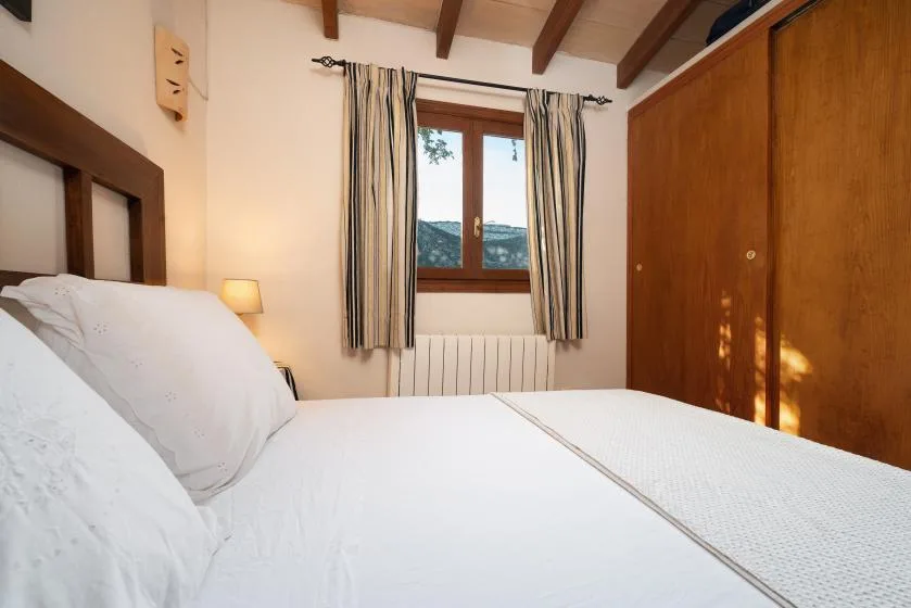 Un dormitorio con una cama, un armario de madera y una ventana con cortinas a rayas.
