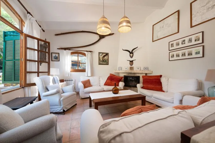 Una sala luminosa con asientos blancos alrededor de una mesa de centro de madera y una chimenea.