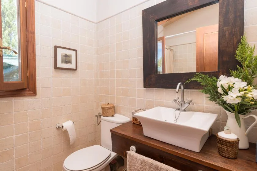 Un baño con azulejos, lavabo, espejo e inodoro.