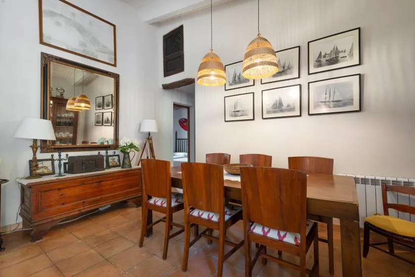 Un comedor con una mesa de madera, sillas y cuadros en las paredes.