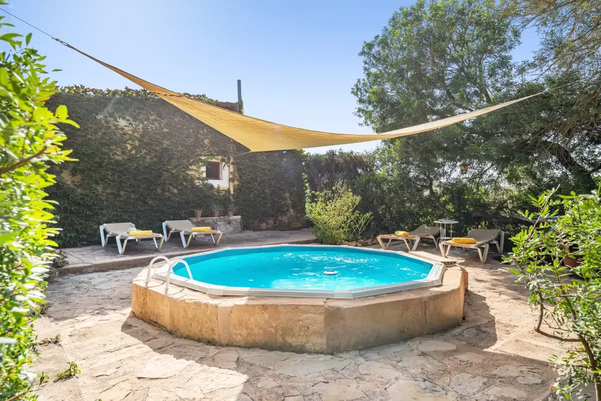 Una piscina al aire libre está rodeada de asientos de patio y árboles frondosos.