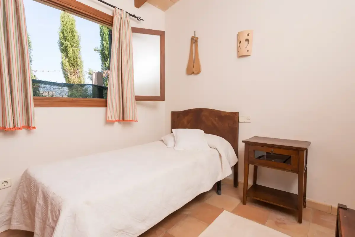 Un dormitorio con una cama individual y una mesita de madera.