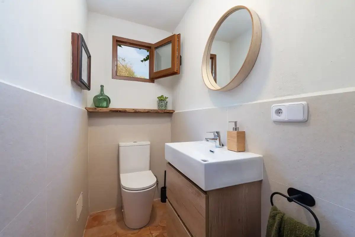 Un baño pequeño con lavabo suspendido y espejo ovalado.