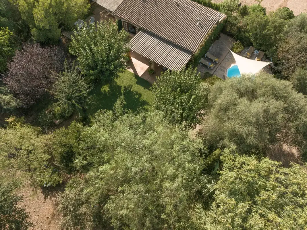 Vista aérea de una casa, una piscina y el jardín que la rodea.