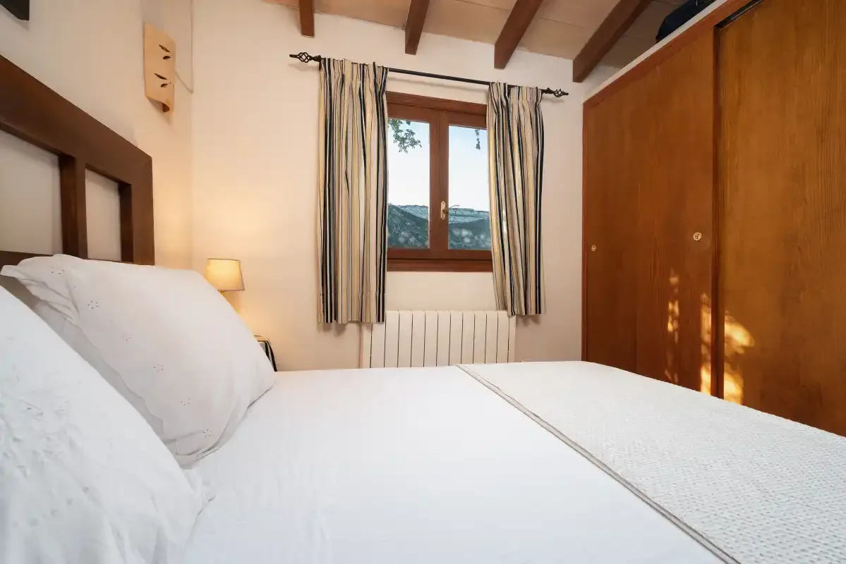 Un dormitorio con una cama, una ventana con cortinas y un armario de madera.