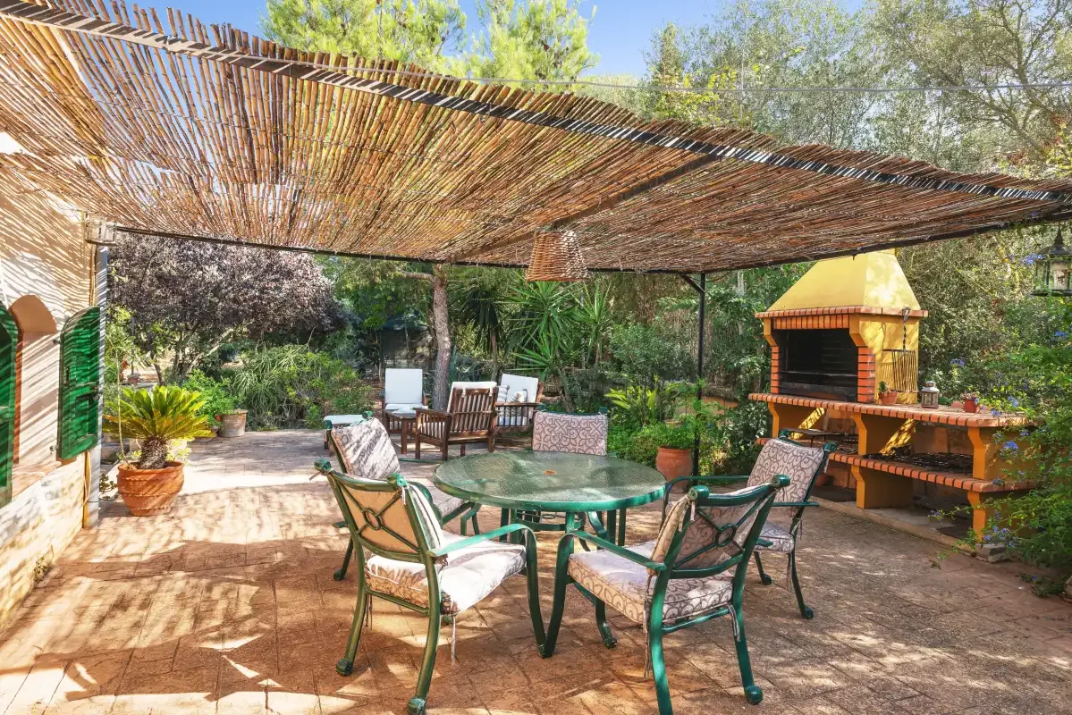 Un patio exterior con asientos bajo un toldo de sombra tejido.