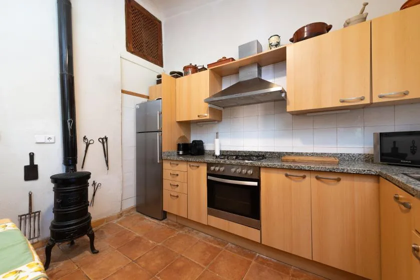 Una cocina con armarios de madera, una estufa y una estufa negra independiente.