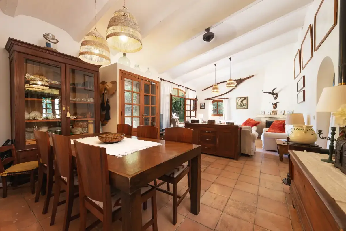 Zona de comedor y sala de estar con una mesa de madera y asientos.