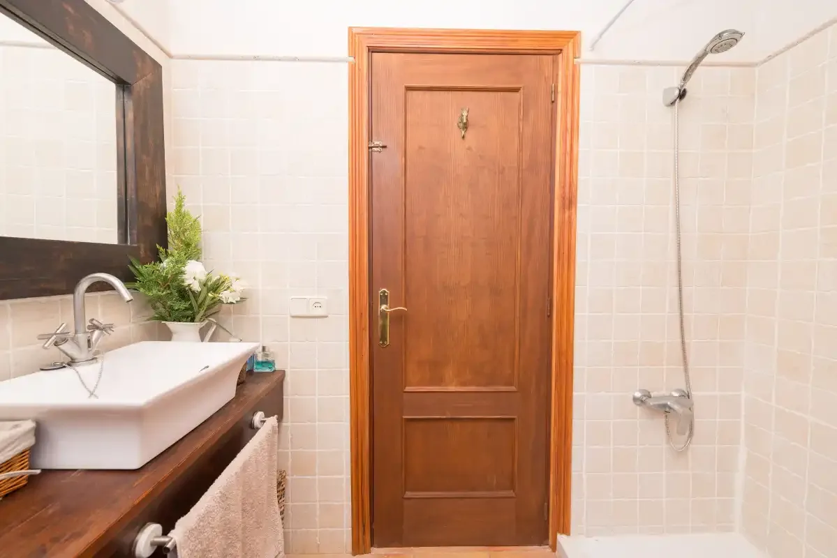 Un baño alicatado con lavabo, espejo y ducha.
