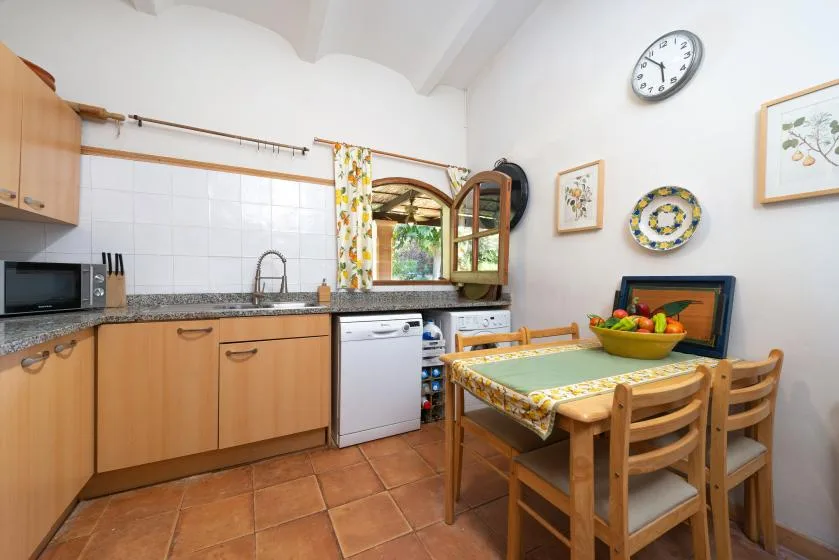 Una cocina con gabinetes de madera y una mesa de comedor junto a la ventana.