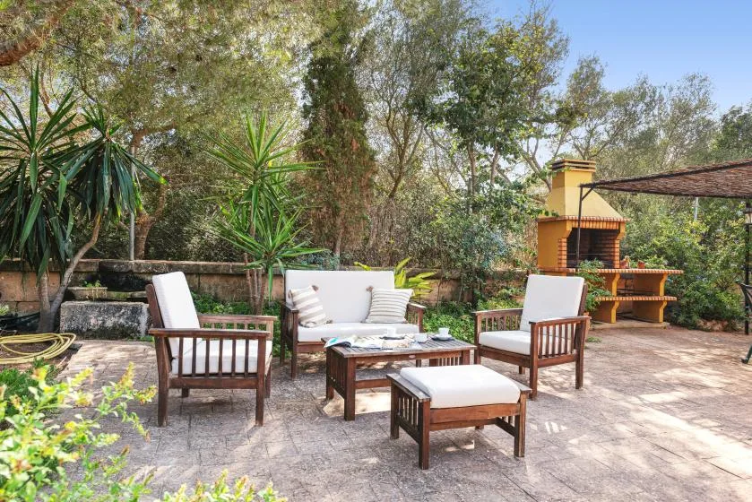 Un patio exterior con asientos acolchados y una zona de barbacoa.