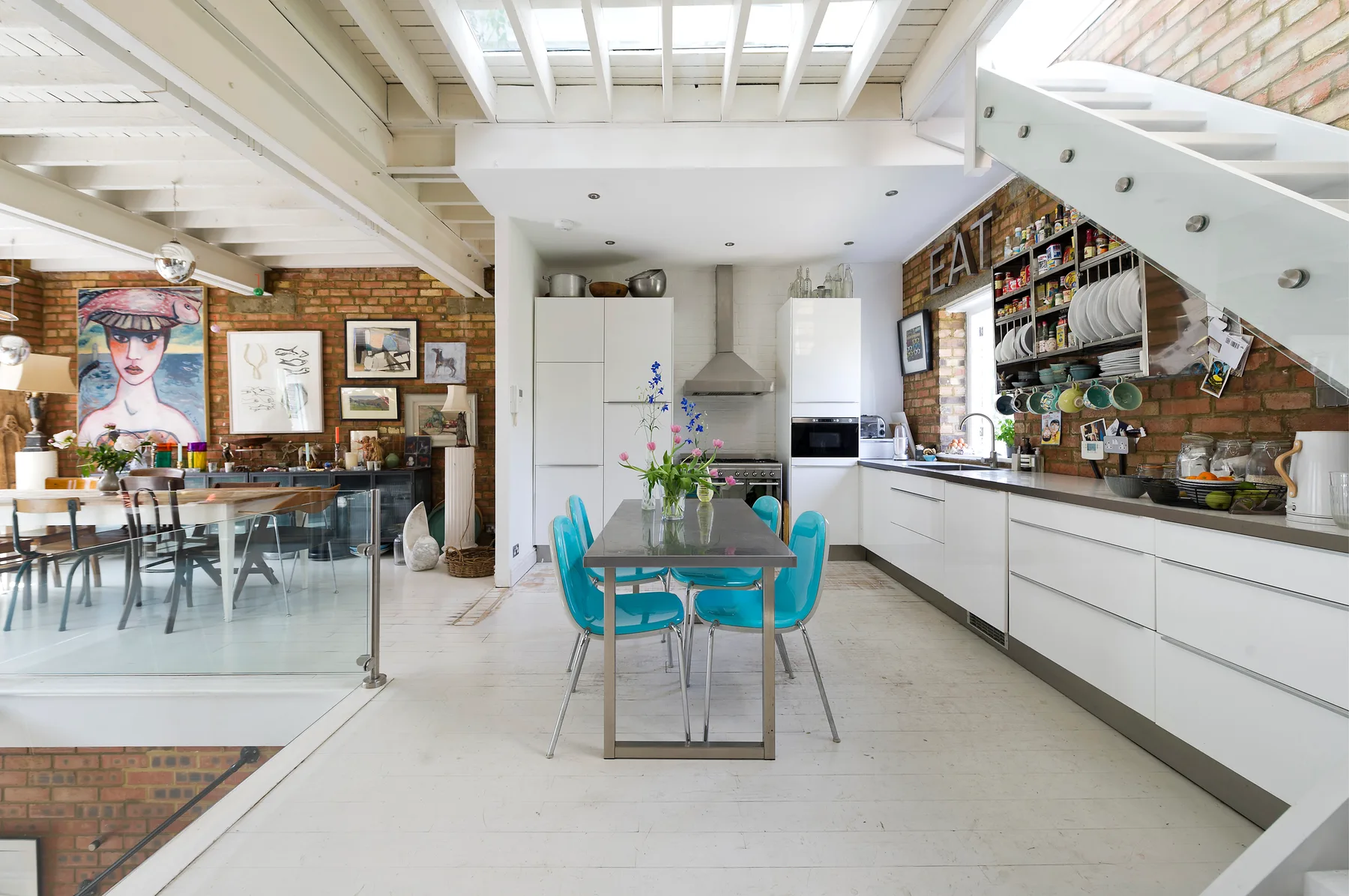 An open-plan kitchen and dining area with a central table and turquoise seating.