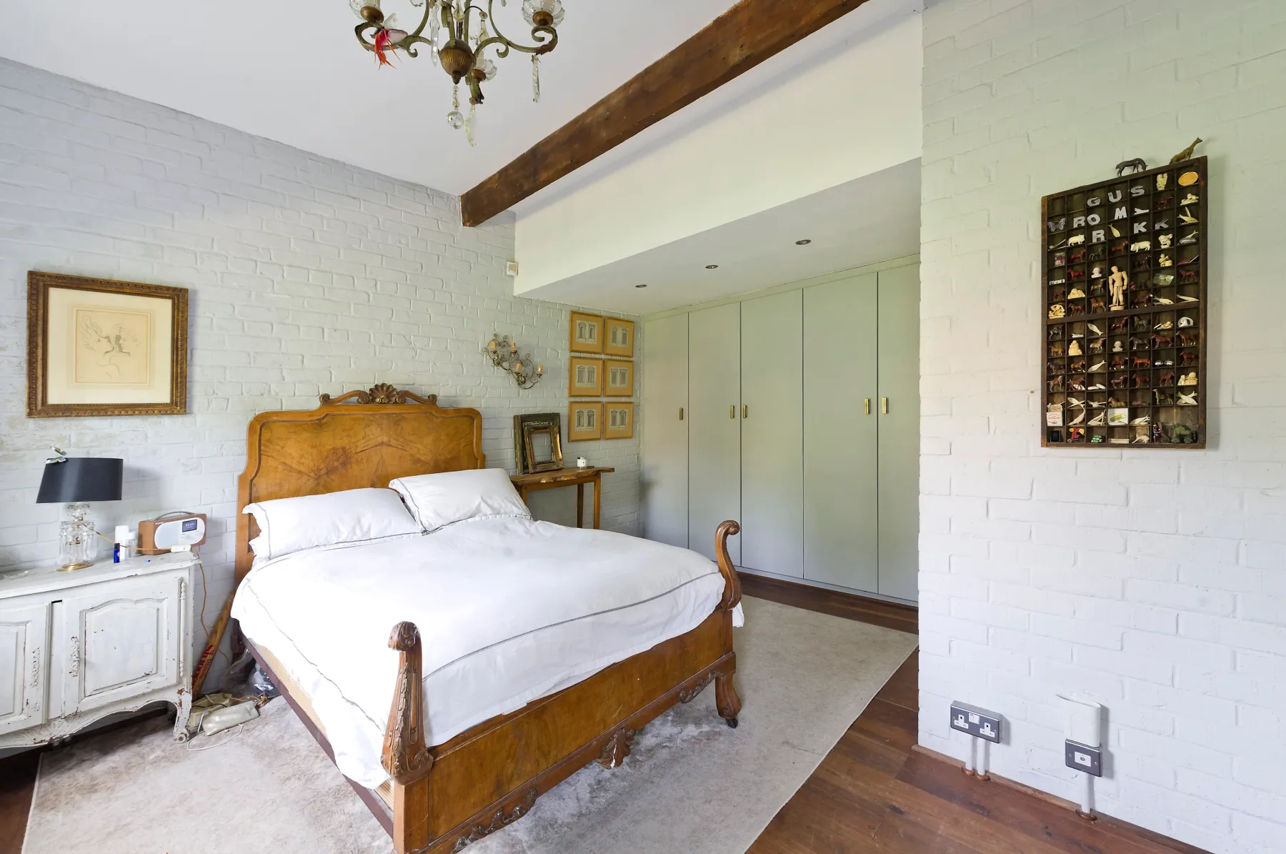 A bedroom with a wooden bed, white bedding, and built-in wardrobes.