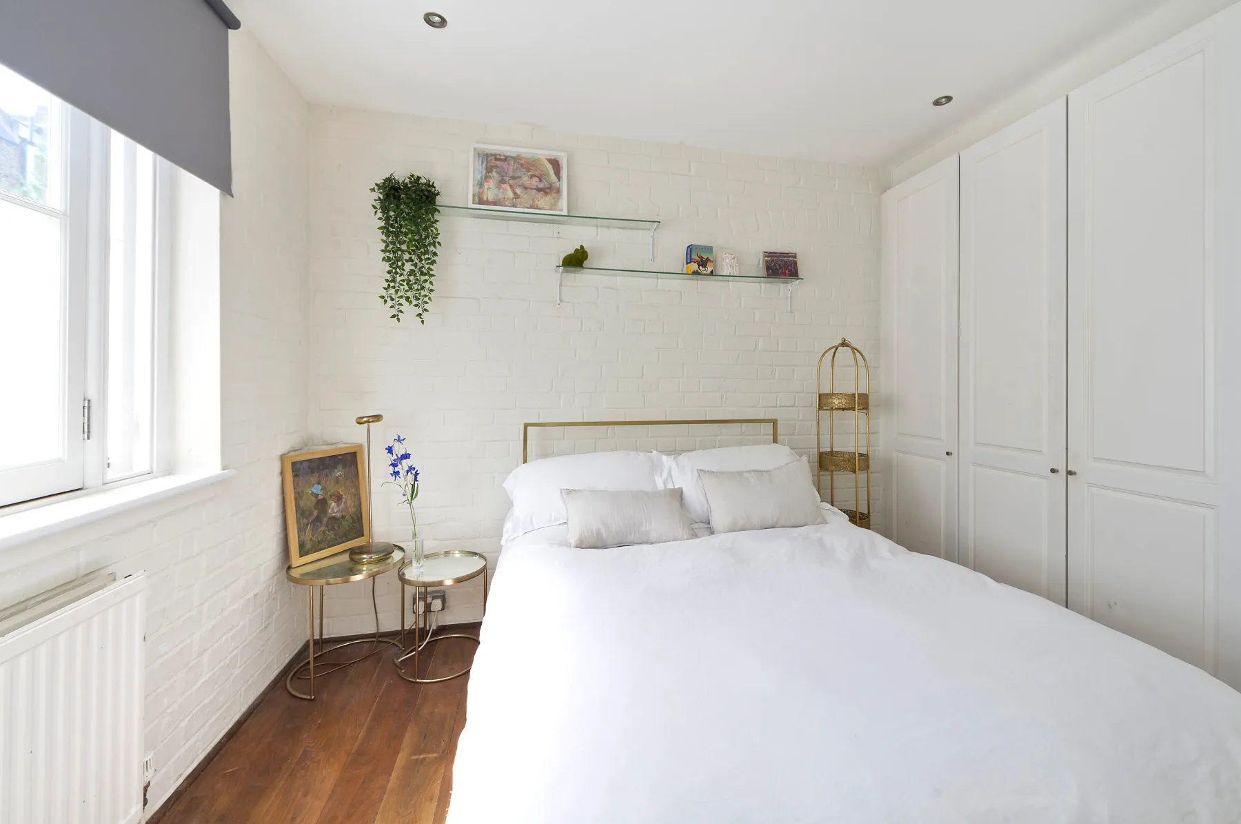 A bright bedroom with a white bed, built-in closets, and a window.