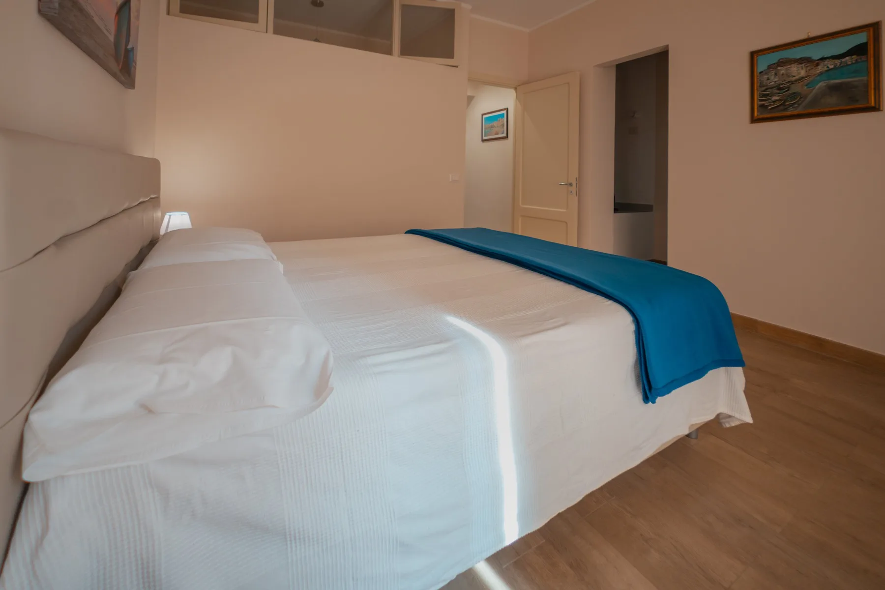 A bedroom with a neatly made bed and a blue blanket.
