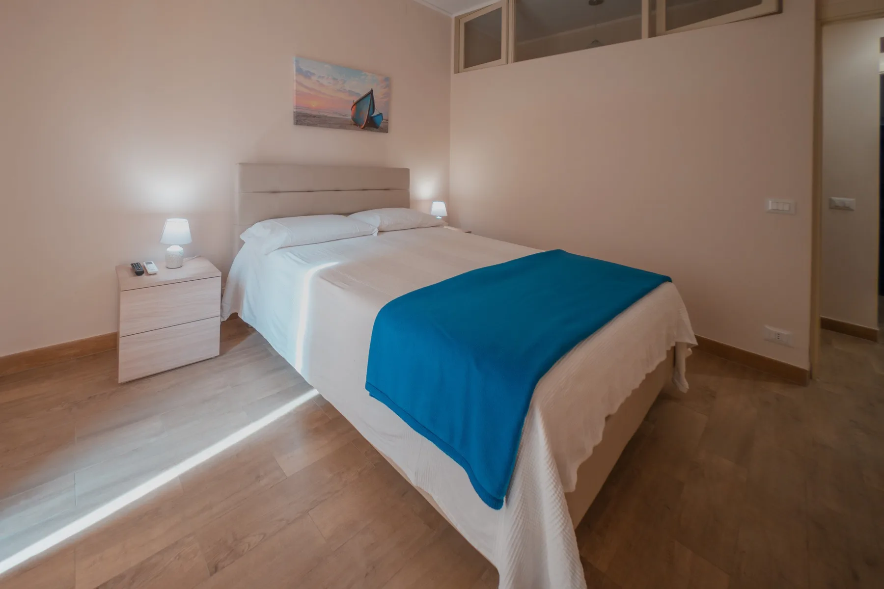A bedroom with a neatly made bed and a blue blanket.