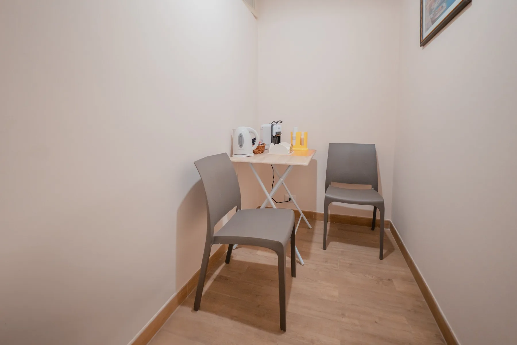 A small seating area with a folding table, kettle, and two chairs.