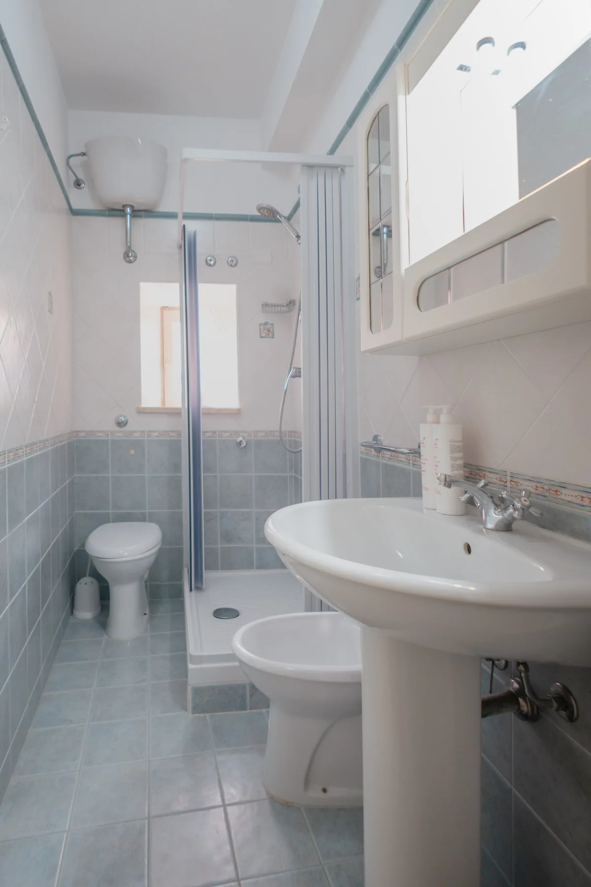 A tiled bathroom with a sink, toilet, and shower area.