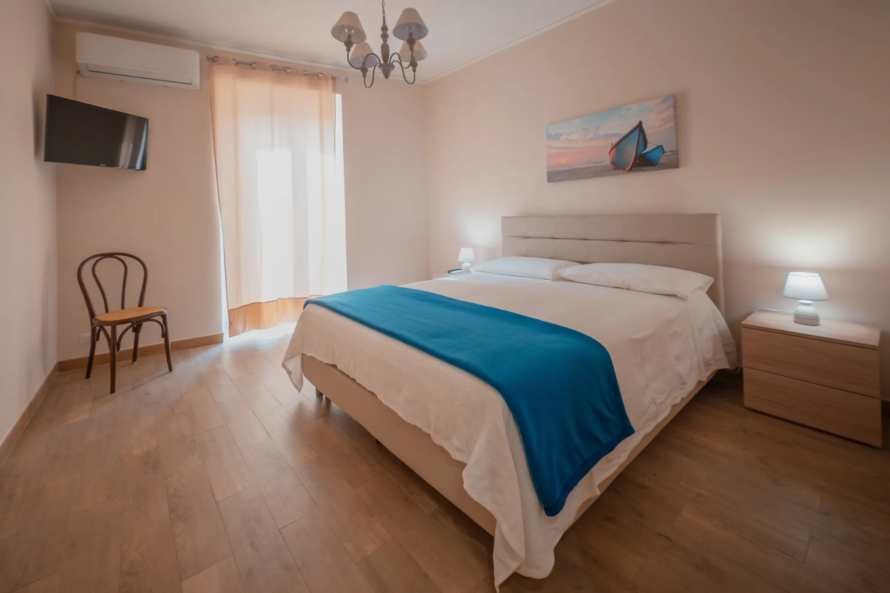 A bedroom with a neatly made bed and a blue blanket.
