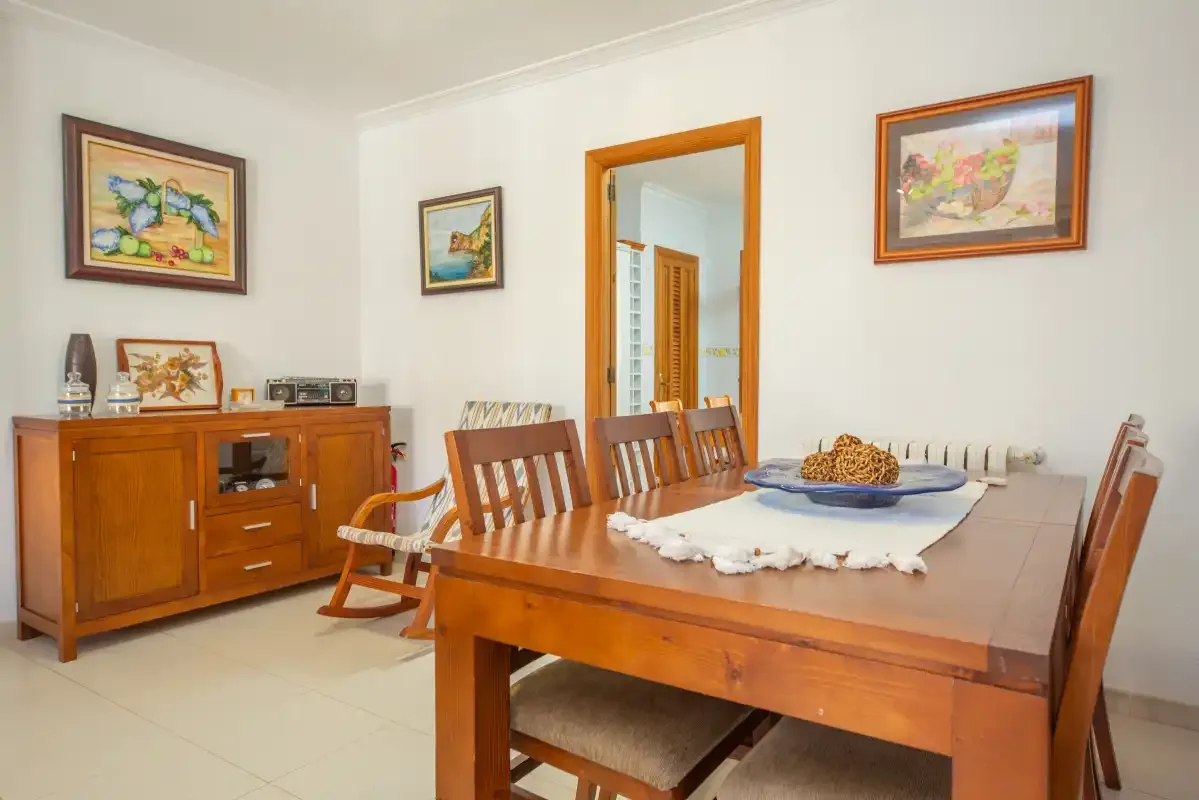 A dining room with a wooden table, chairs, and framed pictures on the walls.