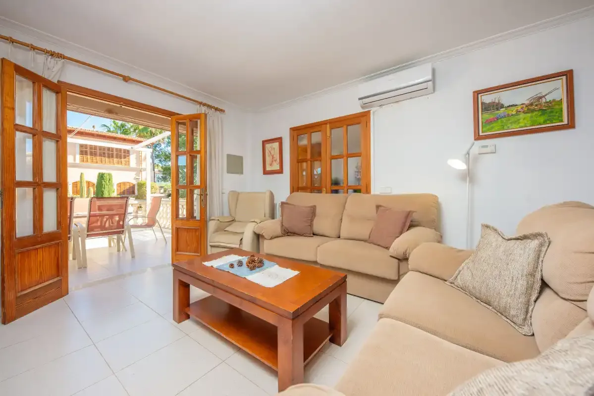 Living room with beige seating and wooden doors opening onto a patio.